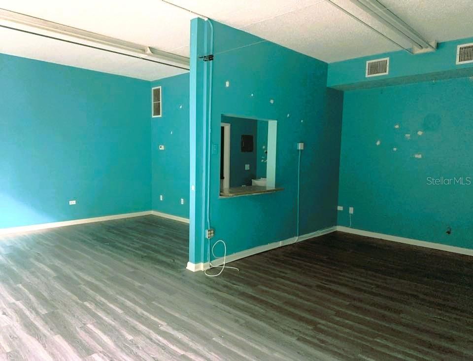 An interior room features bright teal walls, dark wood-look flooring, and a central pass-through window — 2595 TAMIAMI TRAIL, PORT CHARLOTTE, FL