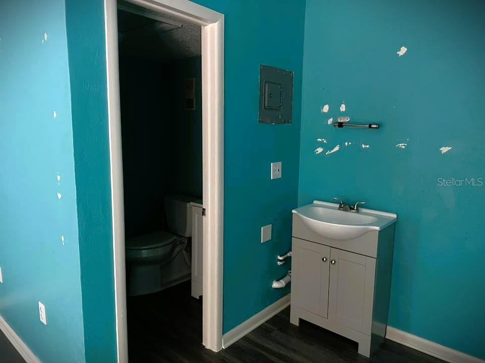 A bathroom features teal walls with peeling paint, a gray vanity, and an adjacent toilet room — 2595 TAMIAMI TRAIL, PORT CHARLOTTE, FL