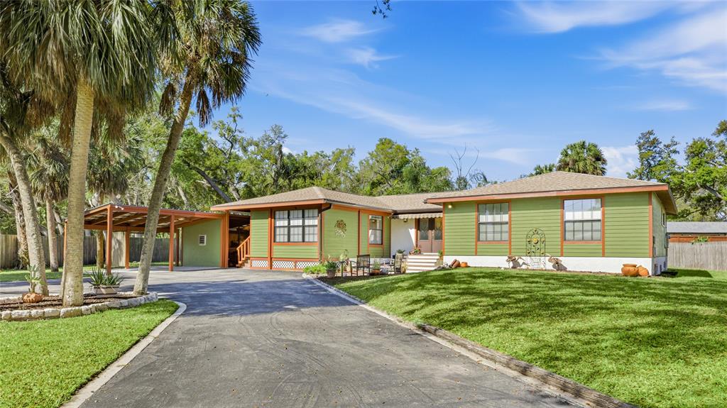 A green, single-story house with a large asphalt driveway and a detached carport — 906 TROPICAL DRIVE, BRADENTON, FL