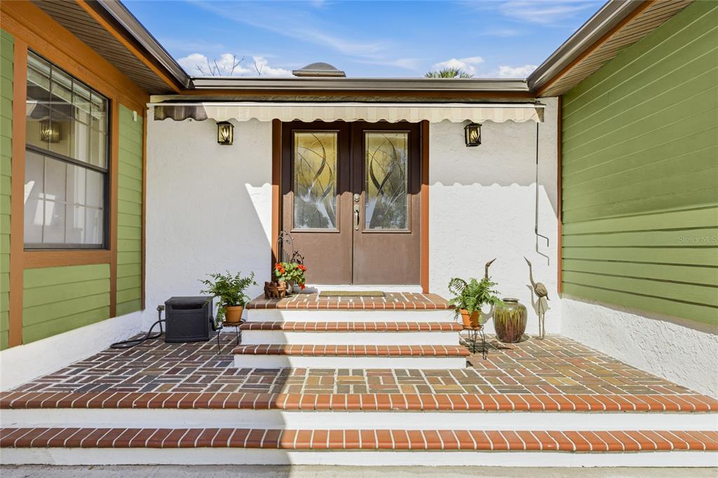 A front entrance features a brick porch, steps, and double doors with decorative glass inserts — 906 TROPICAL DRIVE, BRADENTON, FL