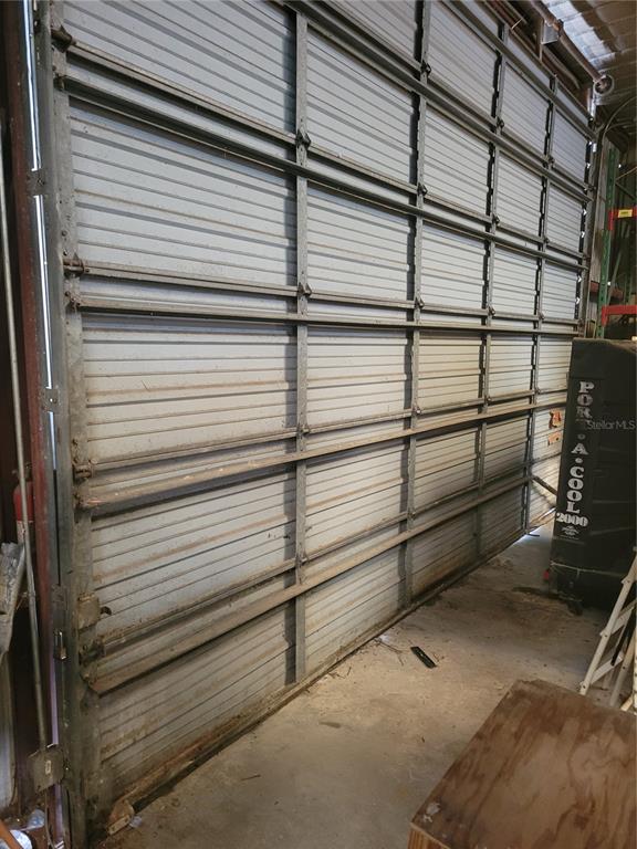 An interior view shows a large, industrial-style metal roll-up garage door with visible support beams — 2437 E CR 478 AVENUE, WEBSTER, FL