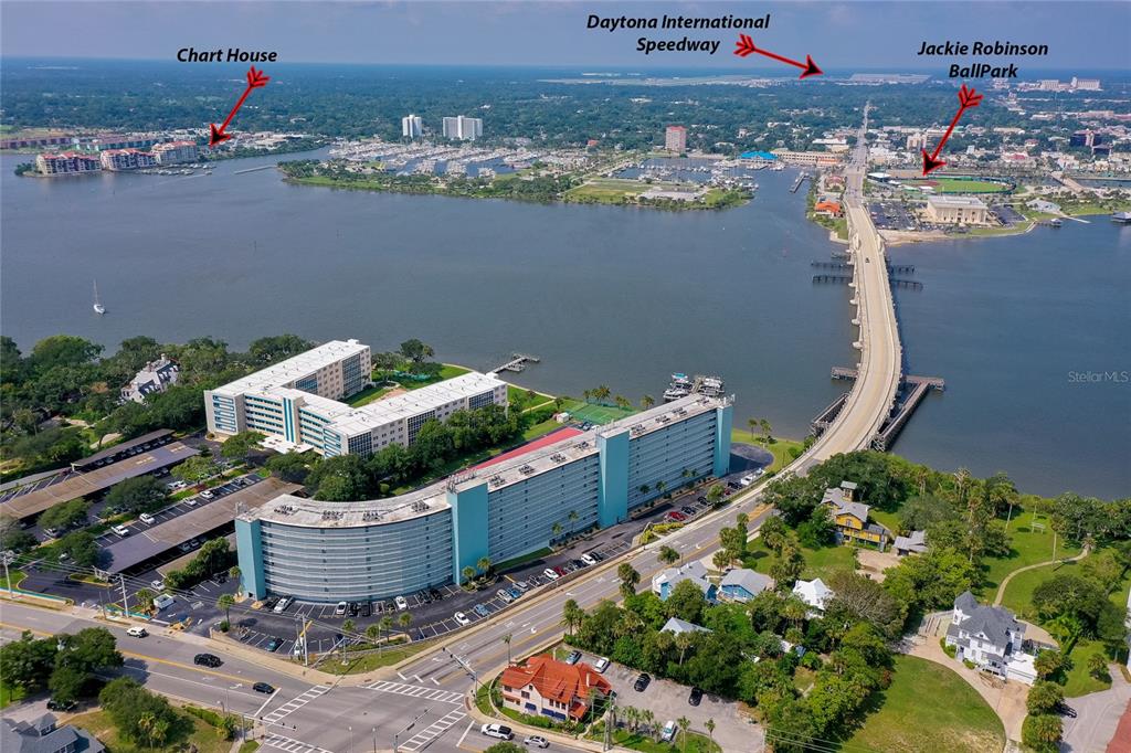 An aerial view shows a large waterfront apartment complex next to a bridge and river — 100 SILVER BEACH AVENUE UNIT 308, DAYTONA BEACH, FL