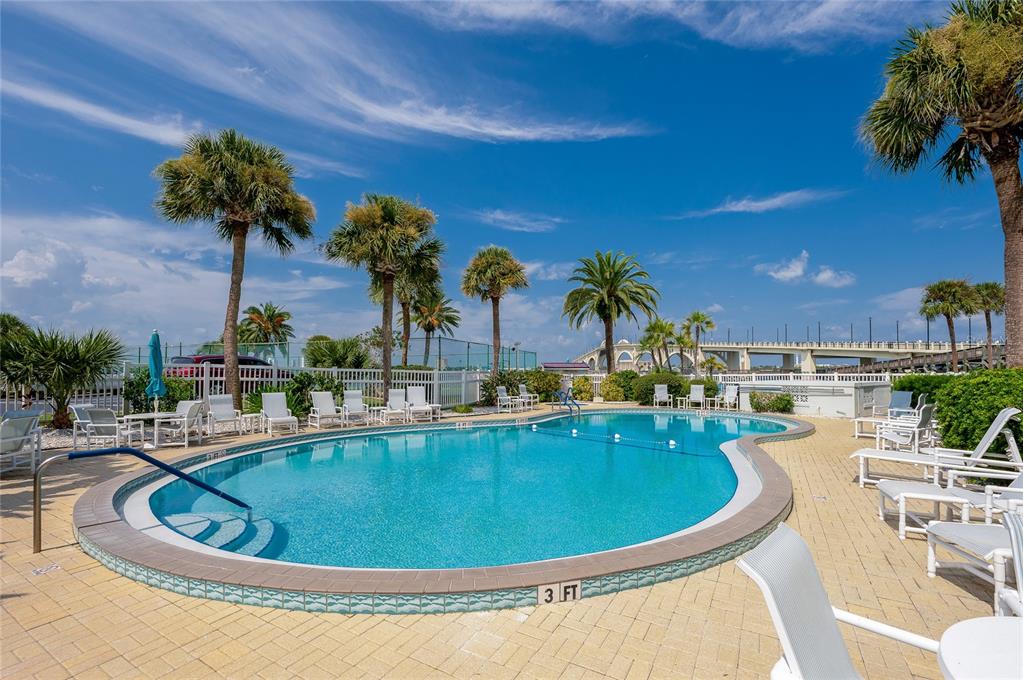A swimming pool with lounge chairs sits on a patio surrounded by palm trees — 100 SILVER BEACH AVENUE UNIT 308, DAYTONA BEACH, FL