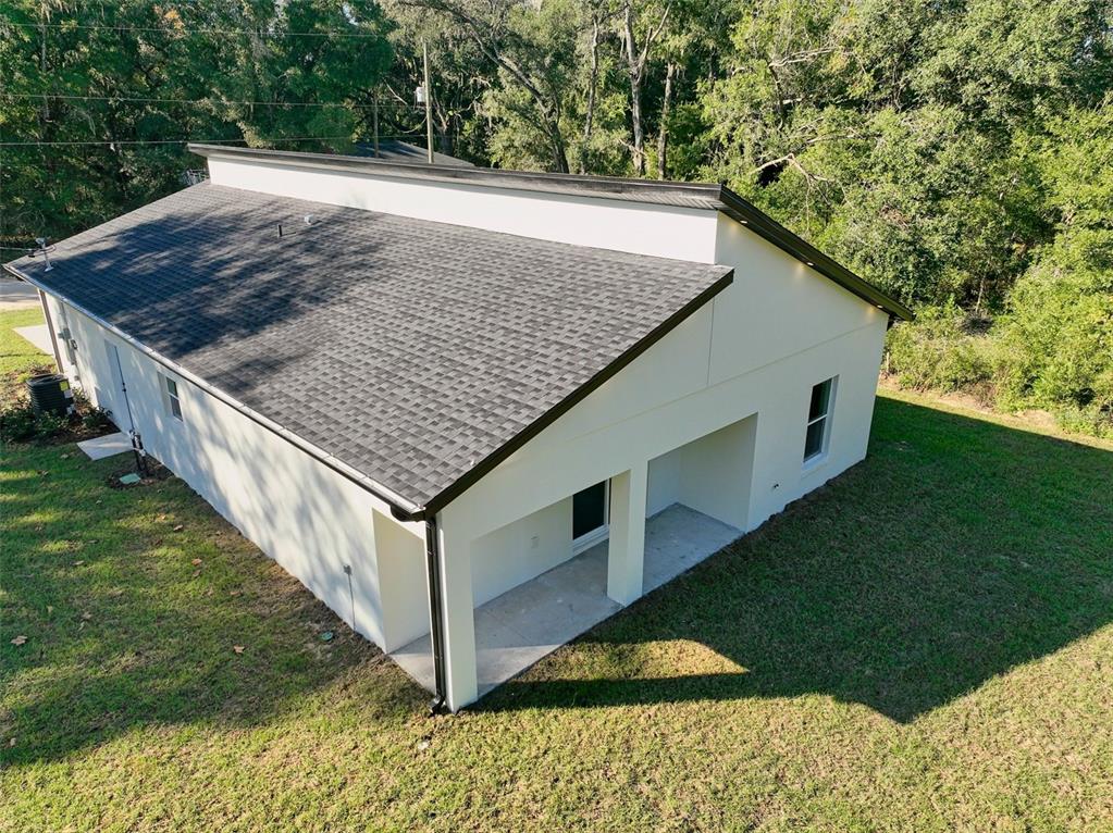An aerial view of a white house with a dark shingled shed roof and porch — 13527 SW 100TH LANE, DUNNELLON, FL