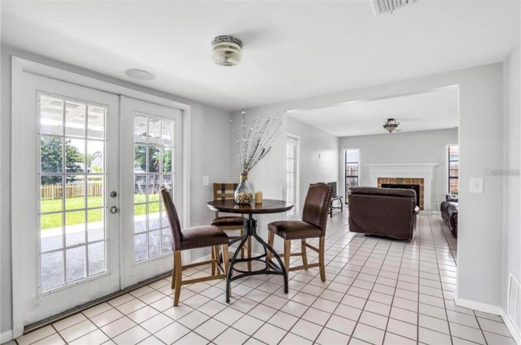 A dining area with a small round table and chairs leads into a living room — 16208 PEBBLEBROOK DRIVE, TAMPA, FL