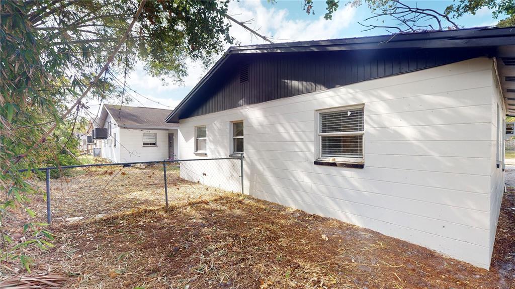A white concrete block house exterior with a dark roof and a chain-link fence — 6710 S JUANITA STREET, TAMPA, FL