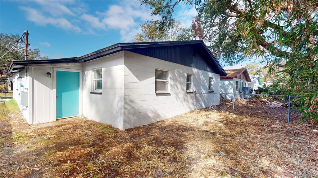 The exterior of a white concrete block house features a bright blue door and fence — 6710 S JUANITA STREET, TAMPA, FL