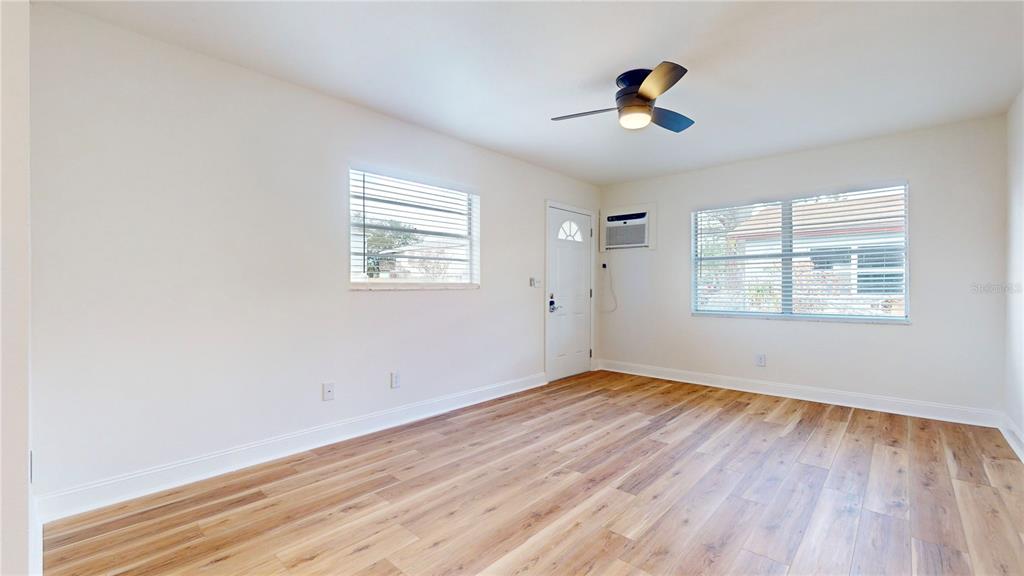 An empty room features light-colored walls, wood-look flooring, a ceiling fan, and two windows — 6710 S JUANITA STREET, TAMPA, FL