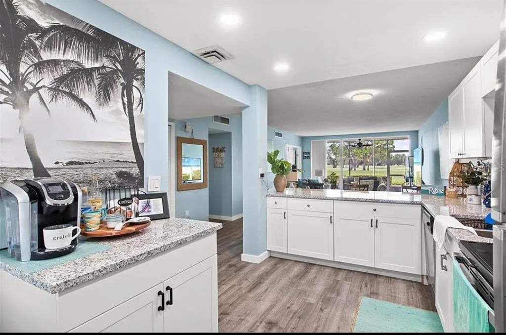 A kitchen with white cabinets, granite countertops, and a view into the living area — 7461 W COUNTRY CLUB DRIVE N UNIT 108, SARASOTA, FL
