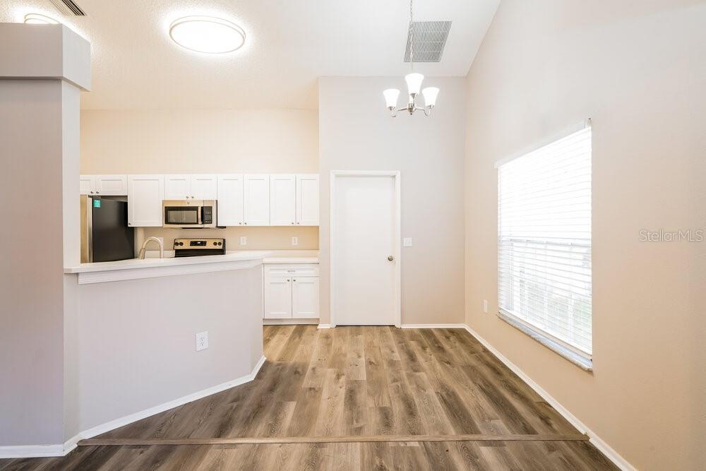 A kitchen with white cabinets and a dining area featuring wood-look flooring and a chandelier — 1434 LAKEHURST WAY, BRANDON, FL