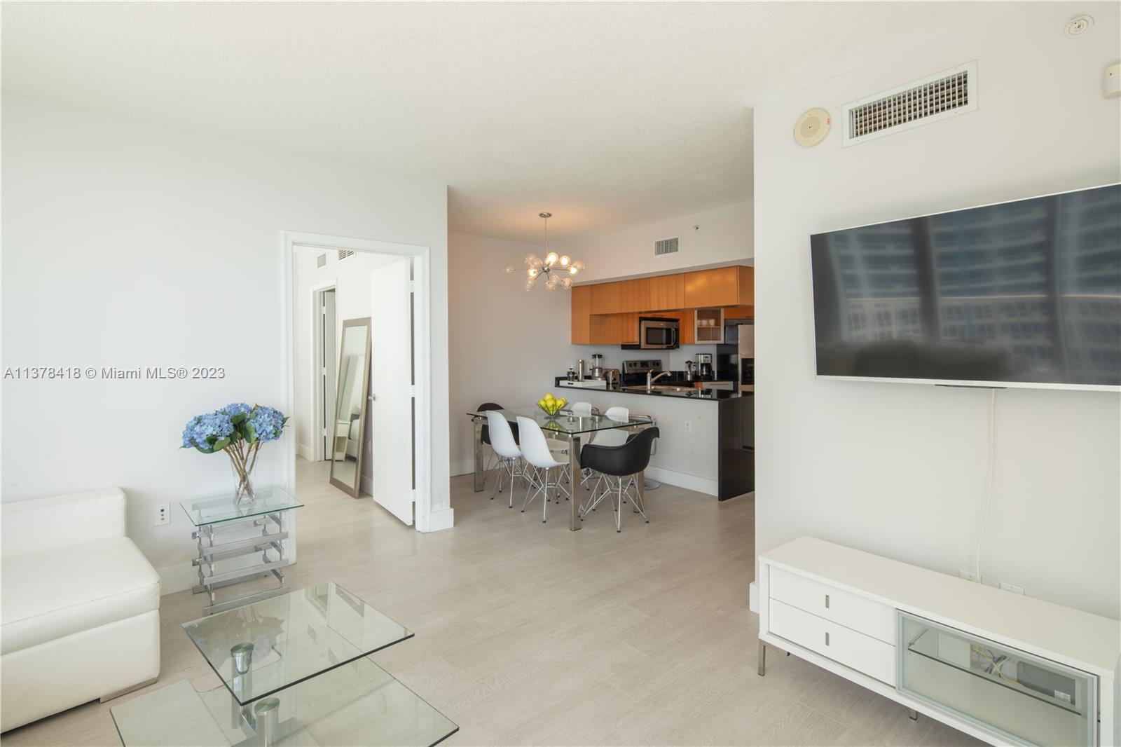 A living room and dining area feature light flooring, modern furniture, and a kitchen — 1750 N Bayshore Dr # 2602, Miami FL 33132, MIAMI, FL