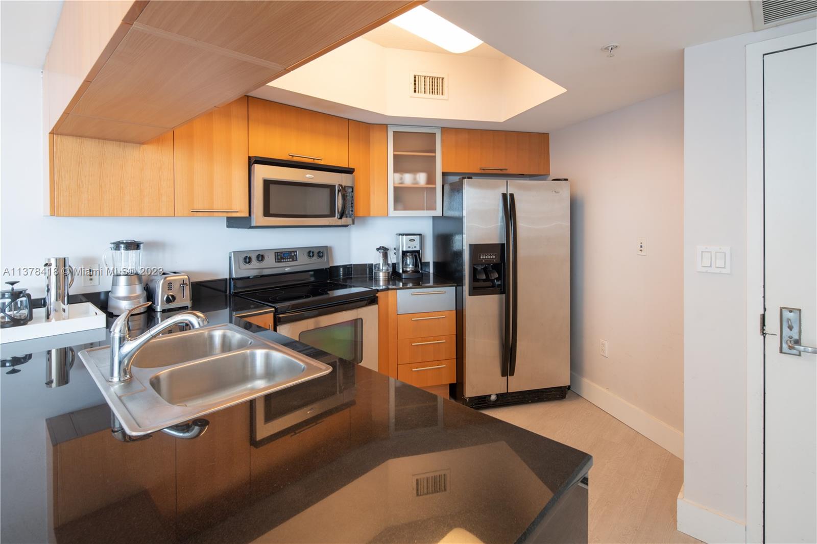 A kitchen features light wood cabinets, black granite countertops, stainless steel appliances, and a double sink — 1750 N Bayshore Dr # 2602, Miami FL 33132, MIAMI, FL