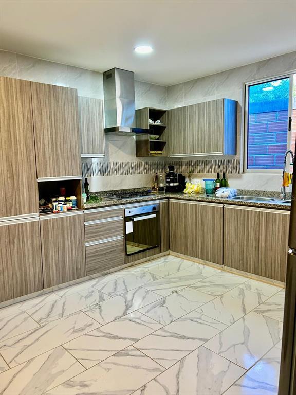 A modern kitchen features wood-grain cabinets, stainless steel appliances, and white marble-patterned tile flooring — Cra 11 #7-72, SANTA VERONICA, ATLANTICO, OC
