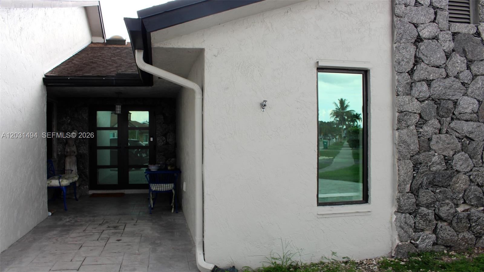 A covered entryway with a stone wall, a glass door, and a single window — 14680 SW 107th Ter, Miami FL 33186, MIAMI, FL