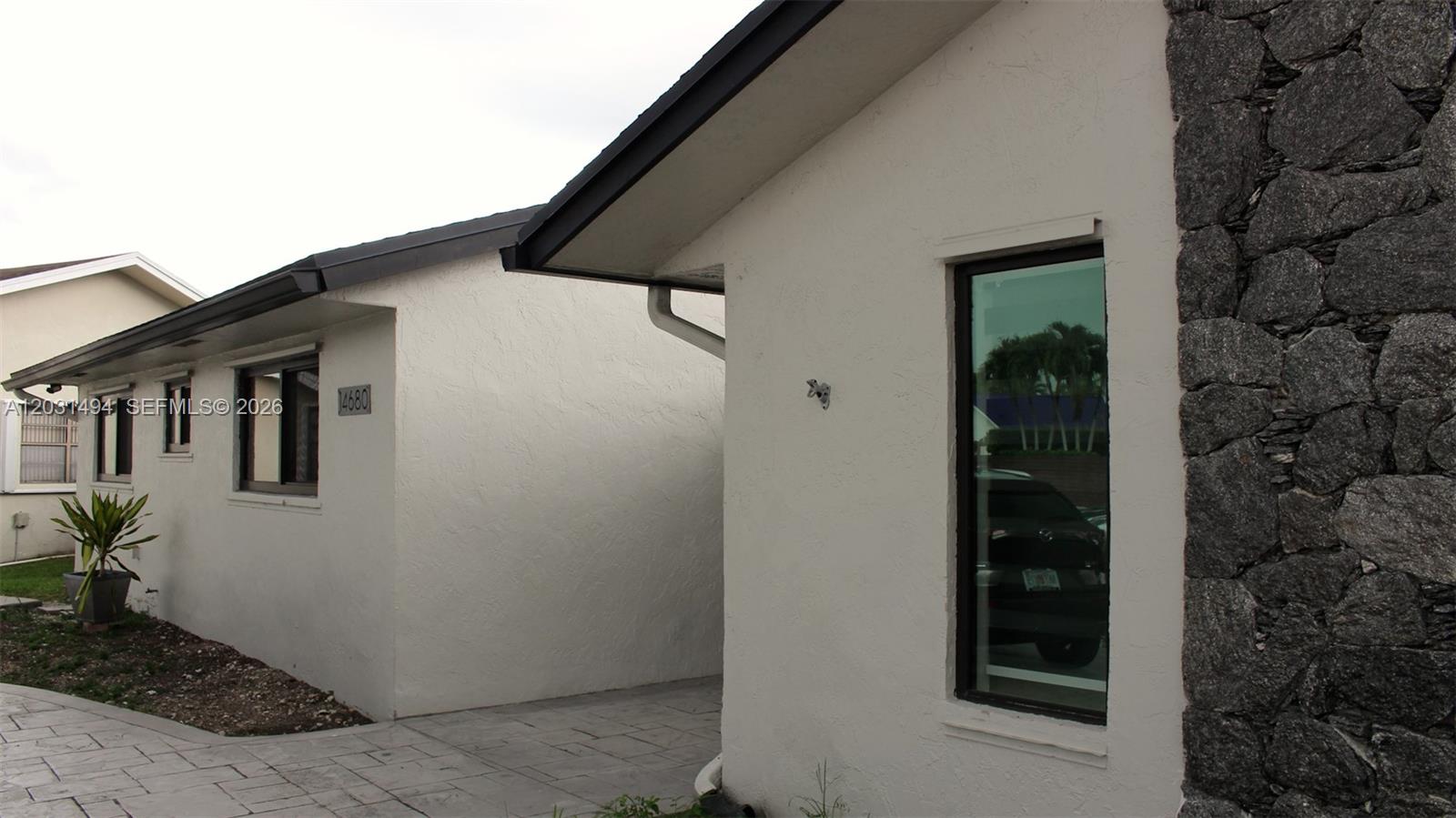 The exterior of a white stucco house features a stone accent wall and windows — 14680 SW 107th Ter, Miami FL 33186, MIAMI, FL