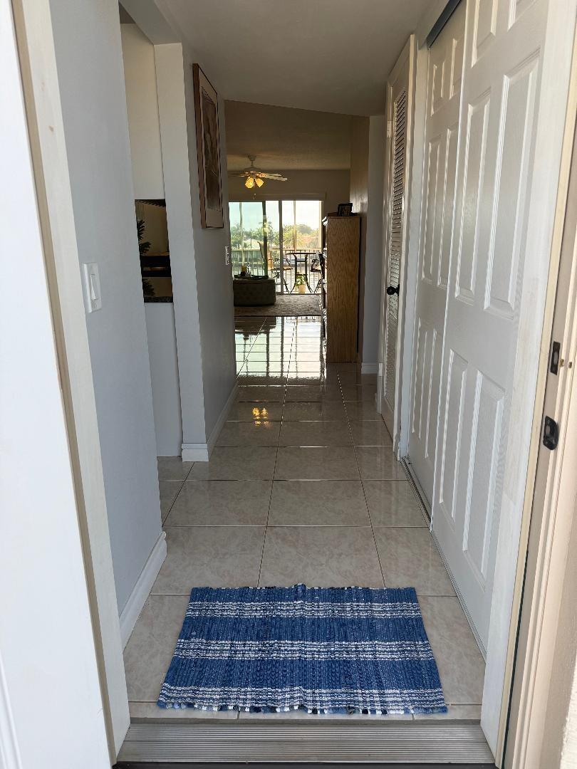 A tiled entryway leads down a hallway toward a living area with a sliding glass door — 646 Snug Harbor Drive # H308, Boynton Beach FL 33435, BOYNTON BEACH, FL