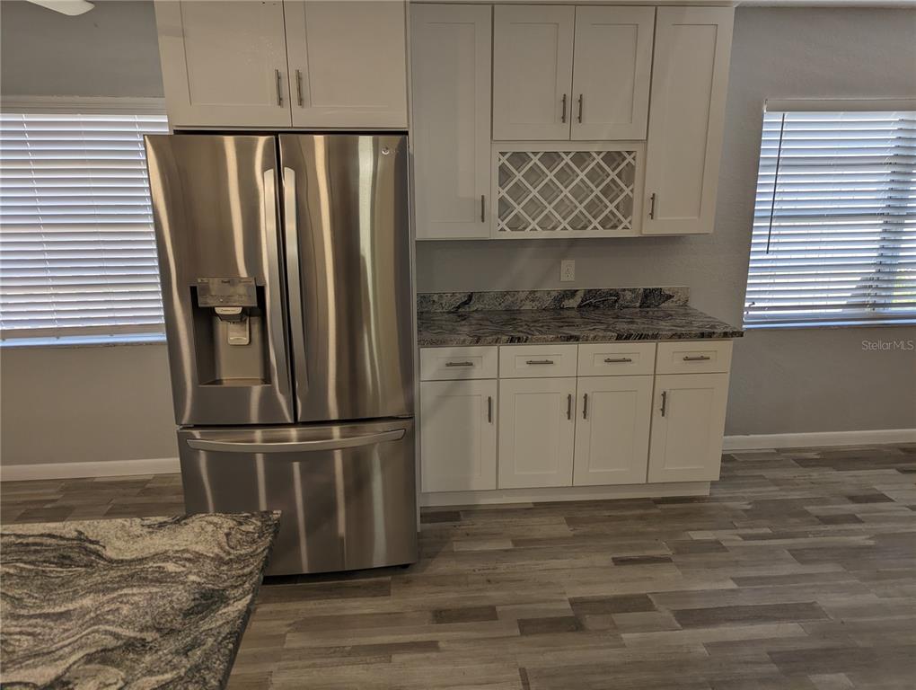 A kitchen features white cabinets, a stainless steel refrigerator, and a granite countertop — 206 N GUNLOCK AVENUE, TAMPA, FL