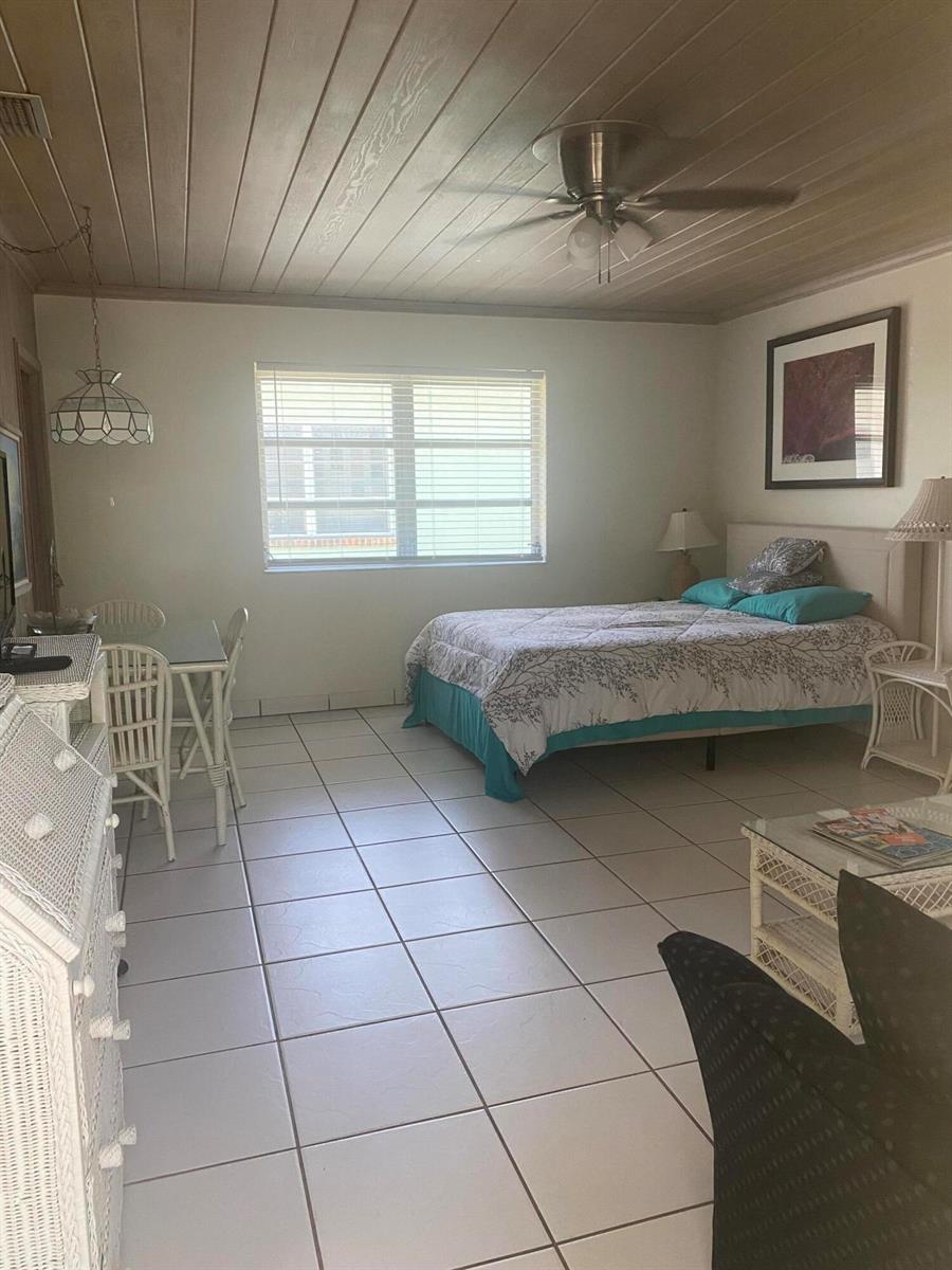 A bedroom with a bed, dining set, tiled floors, and a wood-paneled ceiling — 30 Andrews Avenue # 23c, Delray Beach FL 33483, DELRAY BEACH, FL