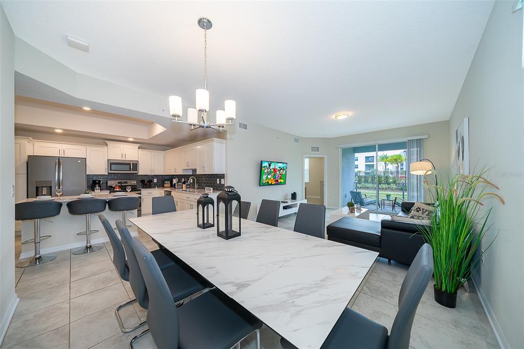 An open-concept dining area features a marble-topped table, modern chairs, and an adjacent kitchen — 3180 PARADOX CIRCLE UNIT 108, KISSIMMEE, FL