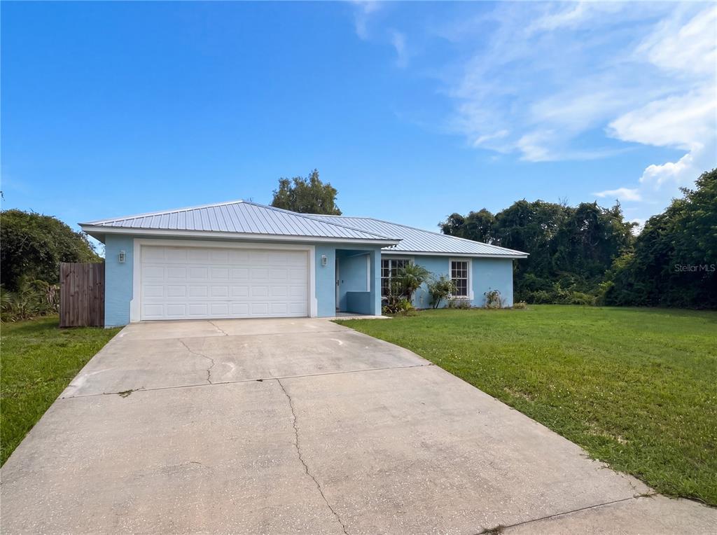 A light blue, single-story house with a metal roof and a concrete driveway — 259 BALTIMORE WAY, LAKE PLACID, FL