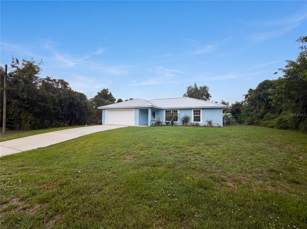A light blue single-story house with a metal roof and a concrete driveway — 259 BALTIMORE WAY, LAKE PLACID, FL