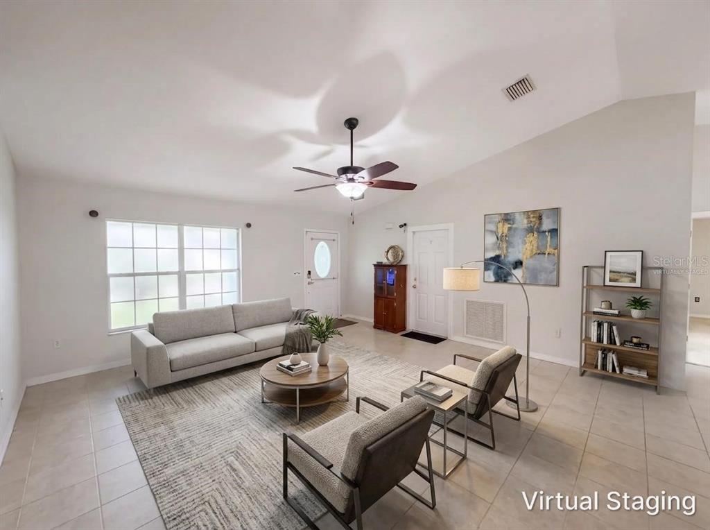 A virtually staged living room with tile floors, a ceiling fan, and a vaulted ceiling — 259 BALTIMORE WAY, LAKE PLACID, FL