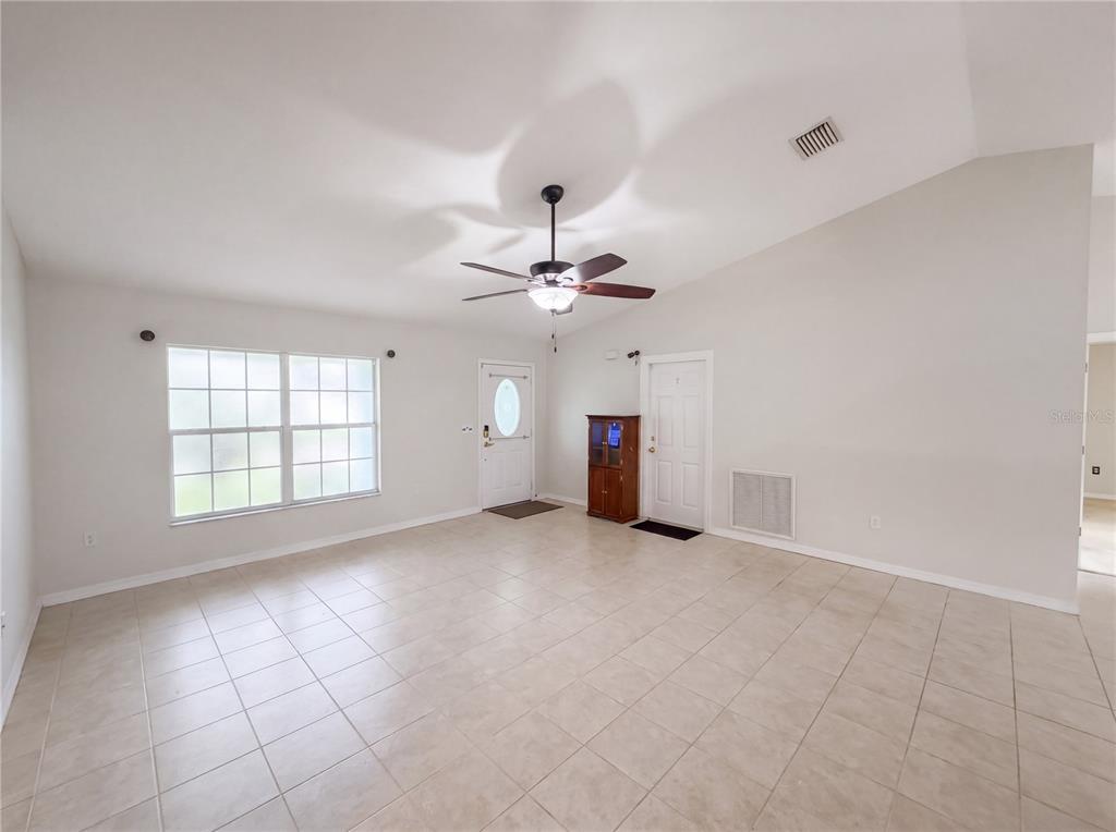 A living room features light-colored tile flooring, a vaulted ceiling, and a ceiling fan — 259 BALTIMORE WAY, LAKE PLACID, FL