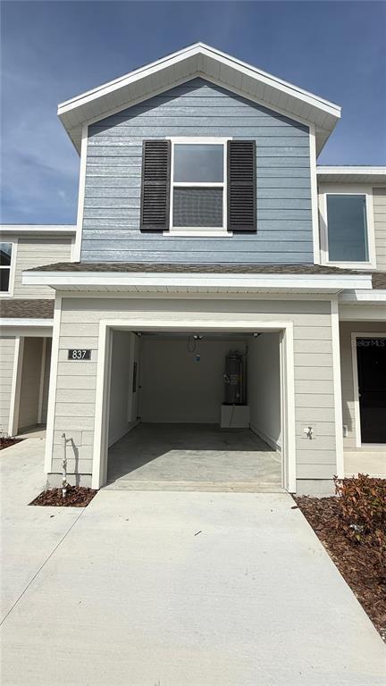 An exterior view of a two-story townhouse featuring a blue-sided upper level and an open garage — 837 LYNX STREET, DAVENPORT, FL