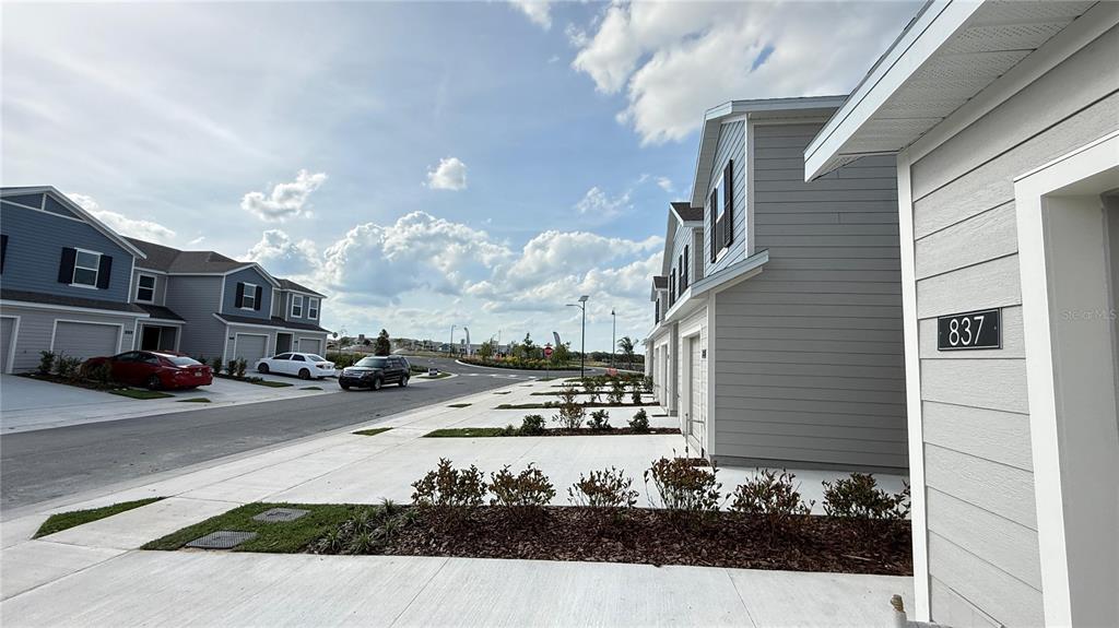 A street view shows a row of modern townhouses with gray siding and concrete driveways — 837 LYNX STREET, DAVENPORT, FL