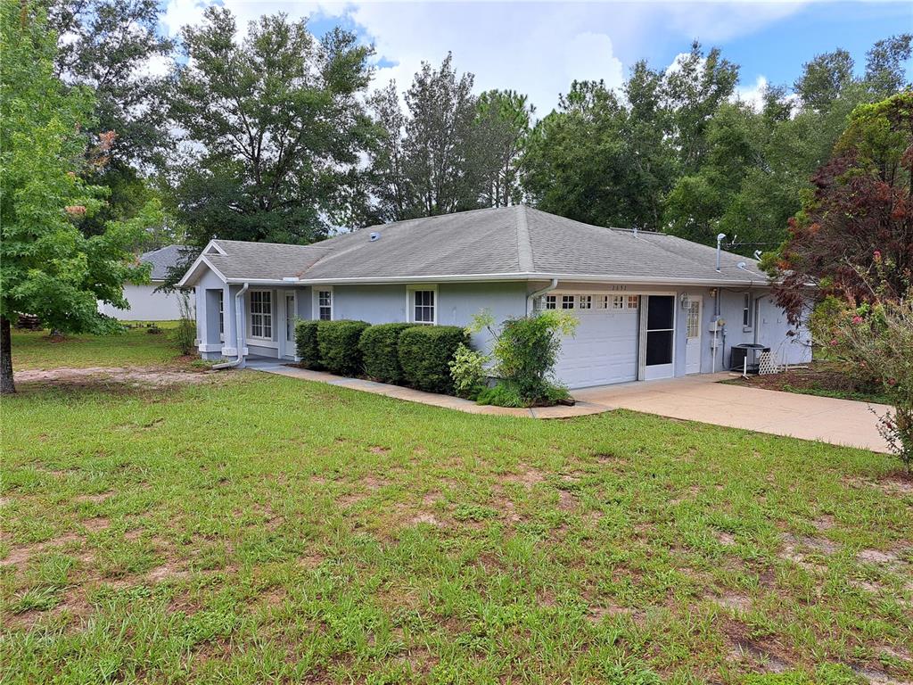 A single-story house with a gray exterior, a garage, and a large front lawn — 2692 W HAMLET PLACE, DUNNELLON, FL