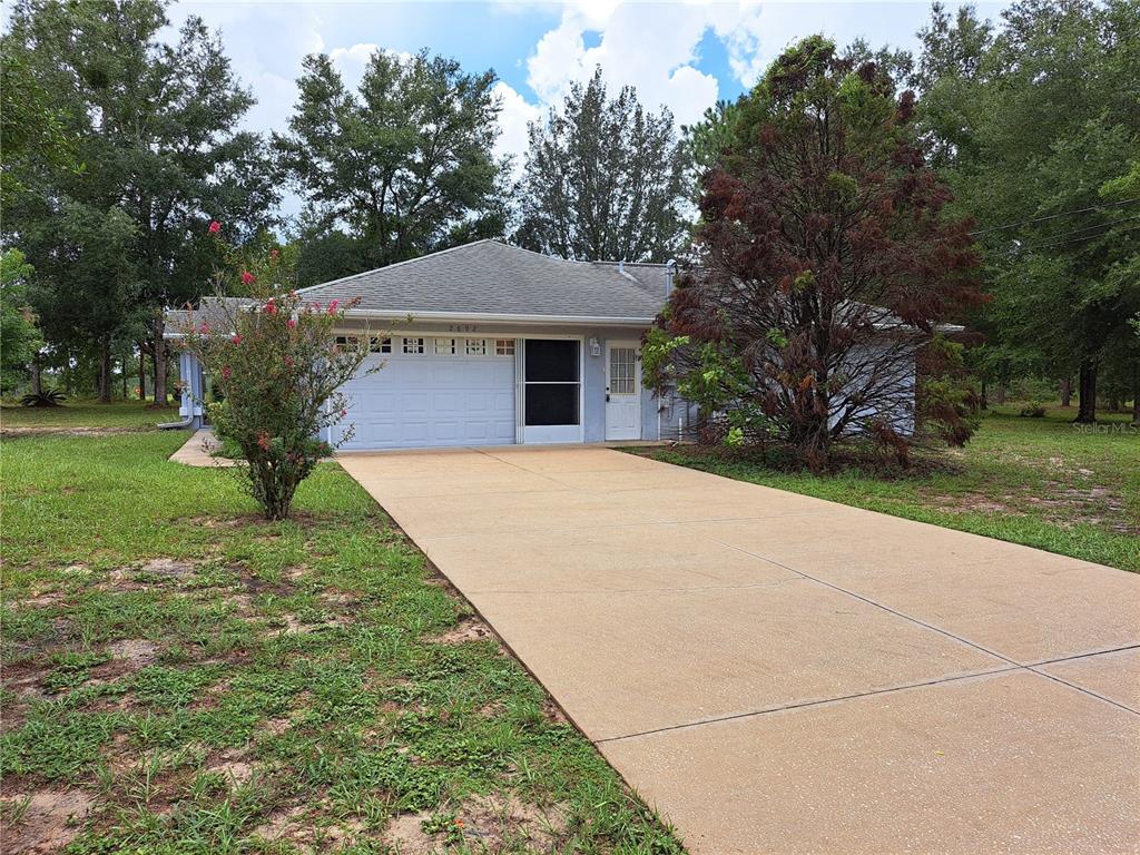 A single-story house with a light blue exterior, a two-car garage, and a concrete driveway — 2692 W HAMLET PLACE, DUNNELLON, FL