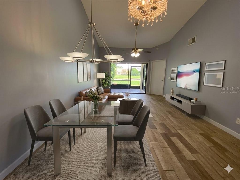 A dining and living area features a glass table, gray chairs, and wood-look tile flooring — 82 LAKEPOINTE CIRCLE UNIT 82, KISSIMMEE, FL