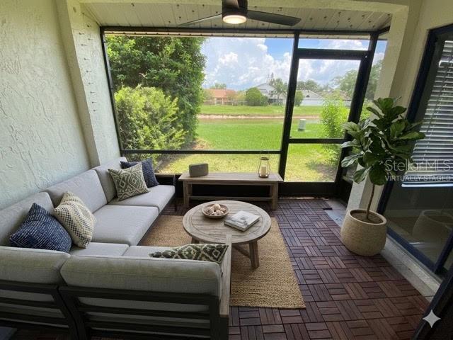 A screened-in patio features a sectional sofa, round coffee table, and views of a pond — 82 LAKEPOINTE CIRCLE UNIT 82, KISSIMMEE, FL
