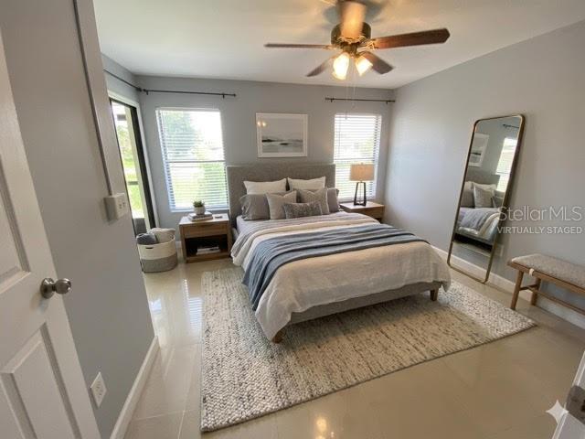 A bedroom with a bed, nightstand, ceiling fan, floor mirror, and tile flooring — 82 LAKEPOINTE CIRCLE UNIT 82, KISSIMMEE, FL