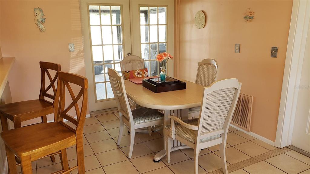 A dining area features a wooden table with four chairs, tile flooring, and glass doors — 375 TERRAPIN, VENICE, FL