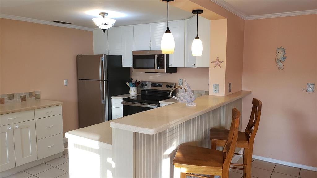A kitchen features white cabinets, stainless steel appliances, a breakfast bar, and light-colored walls — 375 TERRAPIN, VENICE, FL