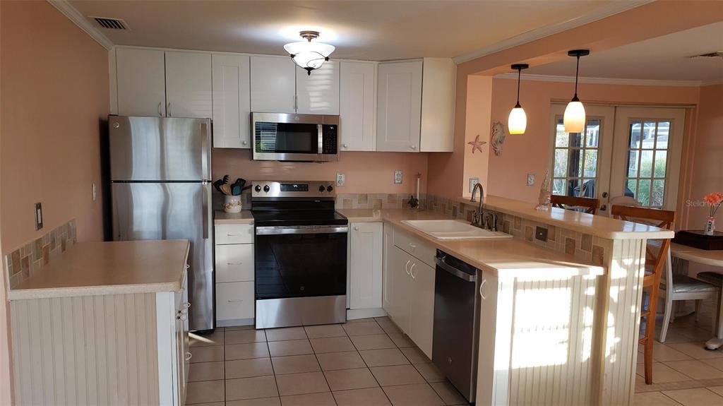 A kitchen with white cabinets, stainless steel appliances, tile flooring, and a breakfast bar — 375 TERRAPIN, VENICE, FL