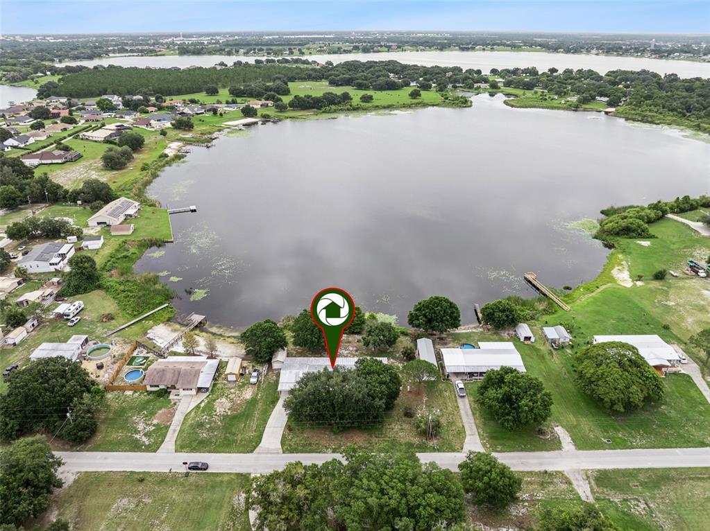 An aerial view shows a house with a large tree on a lakefront lot — 126 BERMUDA COURT, WINTER HAVEN, FL