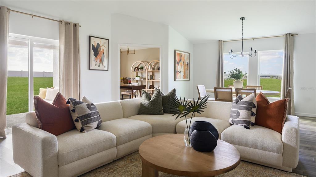 A living room features a large sectional sofa, a round coffee table, and an adjacent dining area — 31670 OYSTER TRELLIS LANE, WESLEY CHAPEL, FL