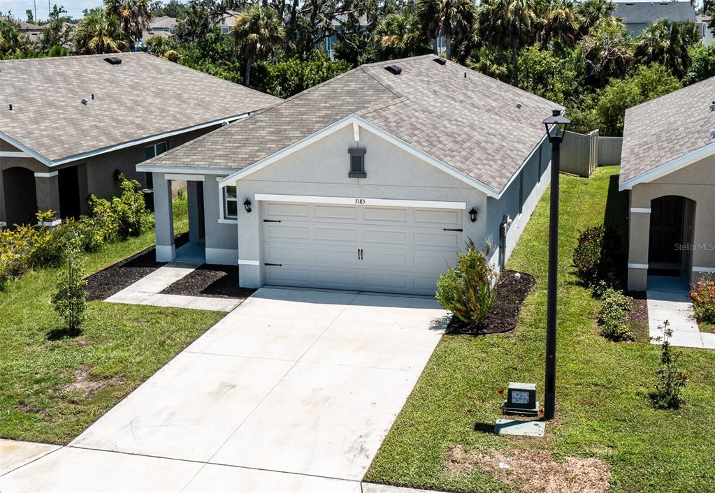 An elevated view of a single-story suburban house with a two-car garage and driveway — 5185 ROCKY COAST PLACE, PALMETTO, FL