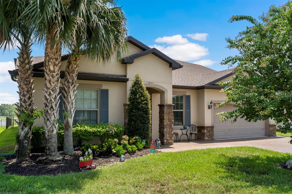 A tan single-story house with a stone-accented entryway, a two-car garage, and palm trees — 1271 PATTERSON TERRACE, LAKE MARY, FL