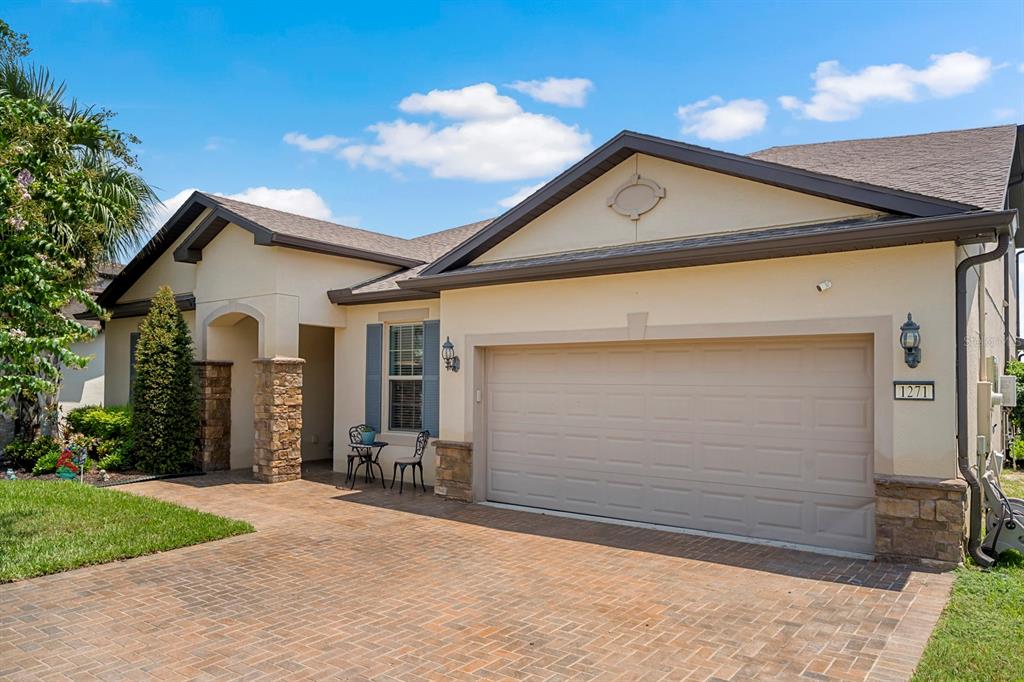 A single-story house exterior features a beige stucco facade, a two-car garage, and stone accents — 1271 PATTERSON TERRACE, LAKE MARY, FL