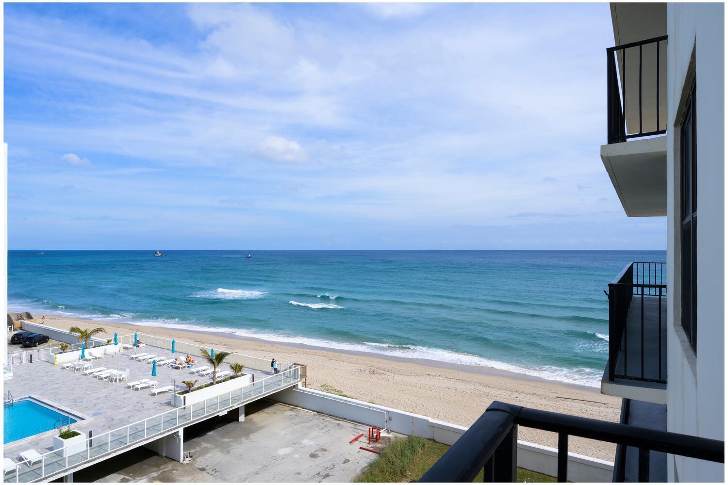 A view from a balcony overlooking a beach, ocean, and a swimming pool deck below — 3456 S Ocean Boulevard # 504, Palm Beach FL 33480, PALM BEACH, FL