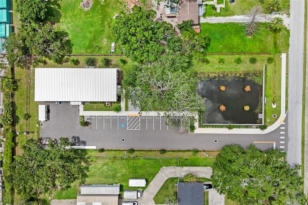 An aerial view shows a commercial building with a parking lot and a retention pond — 1102 S 82ND STREET, TAMPA, FL