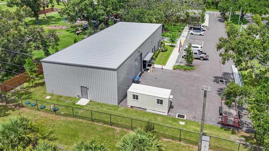 An aerial view shows a metal warehouse building with an adjacent parking lot and container — 1102 S 82ND STREET, TAMPA, FL