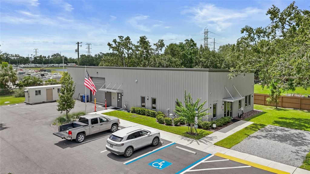 An exterior view of a gray metal commercial building with a parking lot and flag — 1102 S 82ND STREET, TAMPA, FL