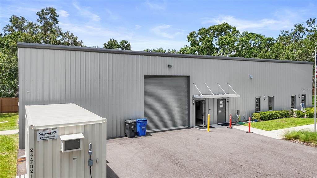 A gray metal industrial building features a roll-up garage door and a side entrance — 1102 S 82ND STREET, TAMPA, FL