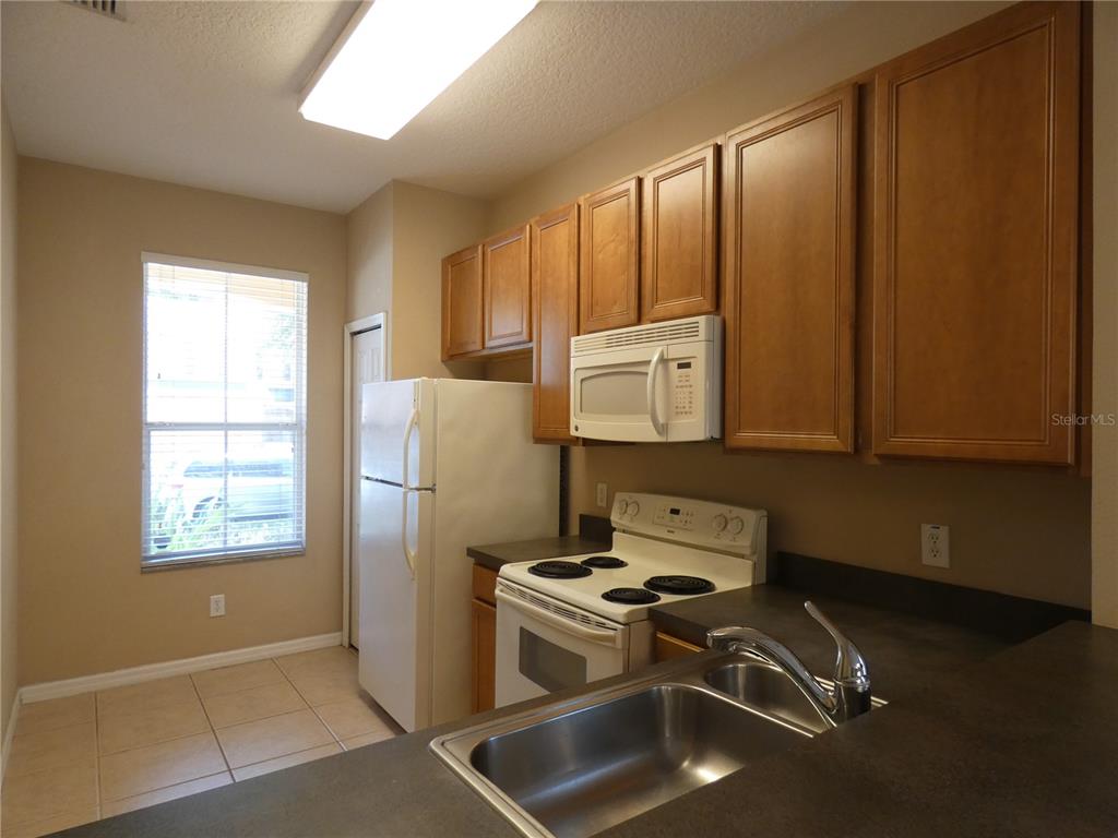A kitchen features wood cabinets, a white refrigerator, a white stove, and a double sink — 2111 RETREAT VIEW CIRCLE, SANFORD, FL