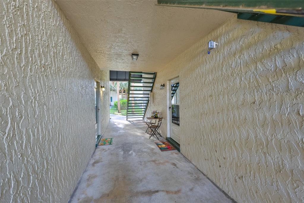An outdoor covered walkway leads to two unit entrances with a metal staircase in back — 4315 AEGEAN DRIVE UNIT 102C, TAMPA, FL
