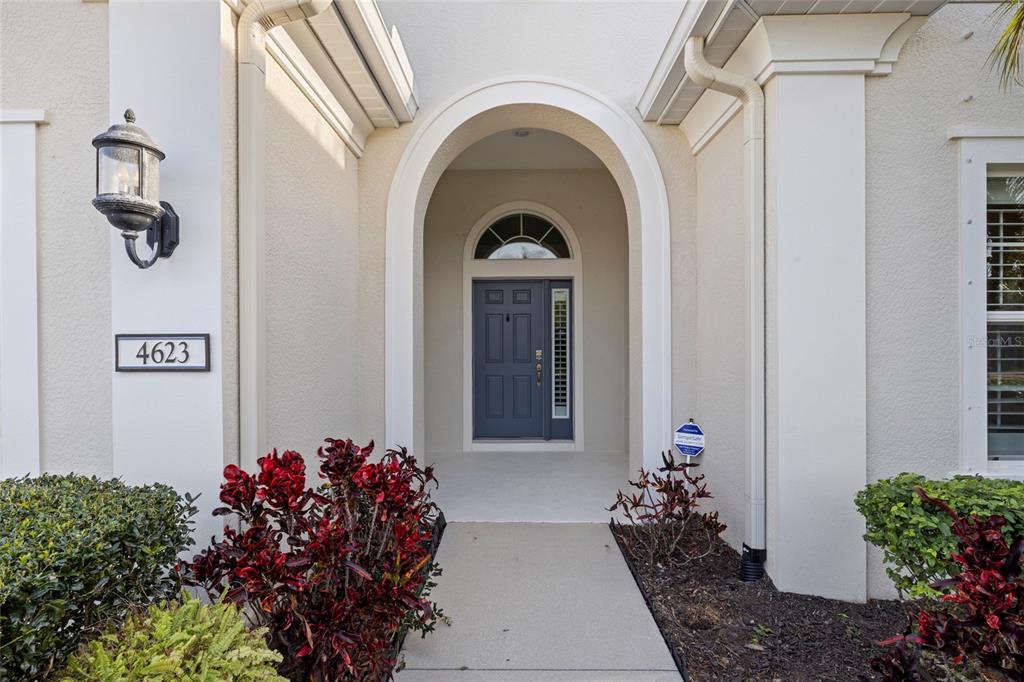 A front entryway features a blue door with a transom window under an arched portico — 4623 CLAREMONT PARK DRIVE, BRADENTON, FL